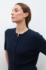 Cardigan gris melange de manga corta con textura estructurada y botones al frente.