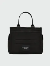 Bolso tote de lona color negro, con asas de mano y correa de hombro. Estampado frontal con el texto "THE TRAVEL BAG MARC JACOBS" en color blanco.