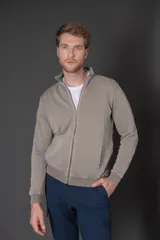 Campera beige de algodón con cierre frontal, cuello alto y bolsillos laterales.