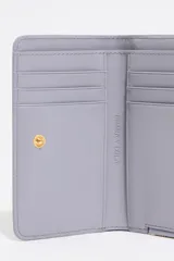 Monedero pequeño con estampado animal print en tonos lila, negro y naranja. Tiene cierre con cremallera dorada y logo de la marca en el frente. Interior con tarjetero y forro con logo grabado.