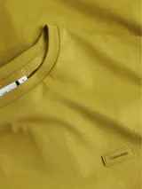 Remera color ocre de algodón orgánico, cuello redondo y manga corta. Tiene un pequeño logo de Calvin Klein en el pecho.