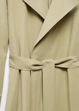 Abrigo color verde oliva, largo hasta la rodilla, con cuello de solapa, manga larga con trabillas, dos bolsillos laterales, abertura posterior en el bajo y cinturón desmontable.