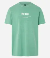 Remera verde con estampa de la marca Kodak y photoprint de playa paradisíaca.