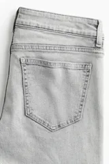 Jean acampanado de tiro bajo, color gris claro, confeccionado en denim levemente elástico.
