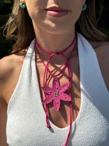 Collar con cordón fucsia y dije en forma de flor rosa con detalles de mostacillas de colores.