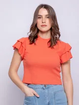 Remera corta de manga corta con volados en los hombros y cuello alto, confeccionada en tela acanalada.