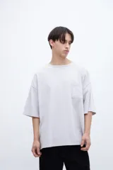 Remera color gris claro, de algodón lavado con textura extra suave, calce boxy y bolsillo en el pecho.