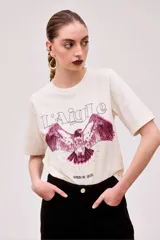 Remera color crudo de corte holgado con estampado de un águila en color fucsia.