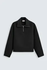 Sudadera negra relaxed fit con cuello alto y cierre frontal de cremallera metálica.