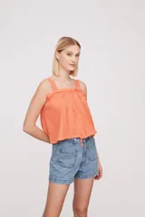 Musculosa color salmón con breteles finos y detalle de puntilla en el escote.