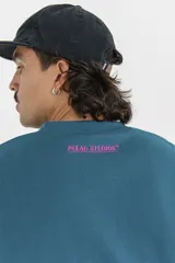 Buzo azul petróleo de corte holgado con cuello redondo y manga larga. Estampa de estrella fucsia en el antebrazo.