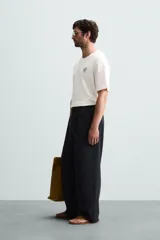 Camiseta blanca de corte holgado, cuello redondo y mangas cortas. Presenta un bordado y estampado combinado en el frente.