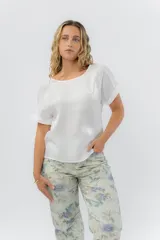 Blusa blanca de corte suelto, mangas cortas con vuelta y escote redondo.