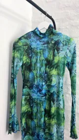 Minivestido de microtul celeste con estampado floral en tonos verdes y violetas, de mangas largas y cuello alto.