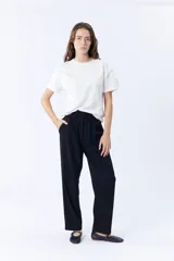 Pantalón de vestir negro, de corte carrot, con pinzas en la cintura y bolsillos laterales.