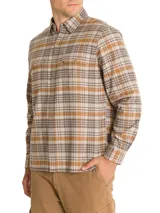 Camisa de franela a cuadros azul, beige y negro, de manga larga con puños abotonados, cuello camisero y cierre frontal con botones de madera. Tiene dos bolsillos de parche con botón en el pecho. Confeccionada en algodón orgánico cepillado.