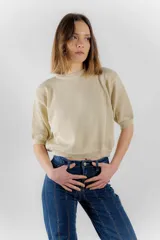 Sweater color dorado de tejido de punto suave con hilos metalizados, corte recto y mangas cortas con puño ajustado.