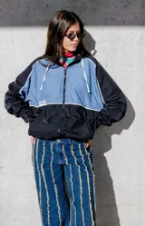 Campera deportiva con capucha, color celeste y negro, con cierre frontal y detalles de ribete blanco en mangas y torso.