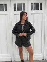 Chaqueta plateada metalizada con cuello camisero, cierre frontal con botones, bolsillos de parche en el pecho y corte recto.