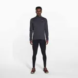 Buzo gris de poliéster reciclado y spandex, con cuello alto y cierre de cremallera hasta el pecho. Tiene mangas largas con orificios para los pulgares y logo de la marca en el pecho.