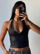 Top negro de ecocuero con escote halter y tachas plateadas.