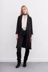 Kimono largo hasta la rodilla, color negro con estampado jacquard. Tiene solapa, botón frontal, tajos laterales y bolsillos ojal con solapa en el frente.