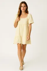 Vestido corto amarillo con bordado calado, de lino y viscosa, corte evasé y cuello redondo.