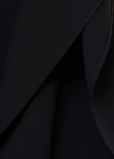 Vestido corto negro con mangas asimétricas y cuello alto.