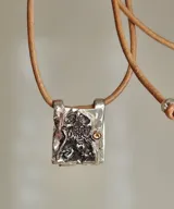 Collar dorado con dije rectangular con imagen religiosa y cristales azules.