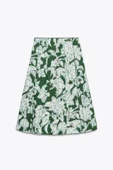 Falda midi de tiro medio con estampado floral en tonos blanco y celeste sobre fondo verde. Presenta detalle de tablas y cierre lateral con cremallera oculta.