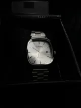 Reloj Casio Quartz plateado con caja cuadrada y pulsera de eslabones.