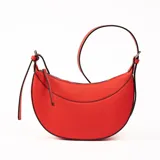 Bandolera pequeña de color rojo vibrante con forma de media luna o media luna invertida. Presenta un acabado texturizado (tipo saffiano) y ribetes negros que definen su silueta. Tiene una correa delgada ajustable para llevar al hombro o cruzada, y un cierre superior con cremallera.