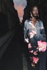 Camisa azul con estampado de flores rosas, cuello solapa y manga corta.