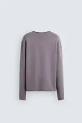 Jersey de hombre color lila, tejido en hilatura de algodón con textura. Tiene cuello redondo, manga larga y acabados en rib con detalle de vuelta.