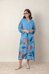 Vestido largo de lino color verde militar con estampado de hojas en tonos azul, naranja y marrón. Tiene cuello mao con botones, mangas tres cuartos y un bolsillo en el pecho.