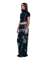 Pantalón unisex de denim 100% algodón con lavado overo (manchas grises sobre negro). Calce wide/relajado, tiro medio, pierna extra ancha y caída larga. Cintura con elásticos laterales, costuras curvas, bolsillos delanteros y traseros curvos, presillas para cinto, cierre y botón metálico.