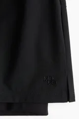 Short de correr negro de doble capa, con cintura elástica y cordón ajustable. Cuenta con una abertura lateral y un short interior con bolsillo en una pierna.