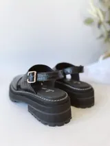 Sandalias negras de cuero con plataforma track y tira trasera con hebilla.