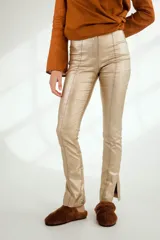Pantalón largo color cobre de corte ajustado, con costuras verticales al frente y aberturas en los tobillos.