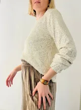 Blusa de lentejuelas color crema, de mangas largas con puños elásticos.