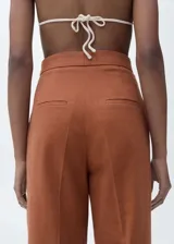Pantalón de vestir color ladrillo, de corte recto y tiro alto, confeccionado en mezcla de algodón y lino. Presenta cierre frontal con cremallera, doble gancho y botón interior, dos bolsillos laterales y forro interior.