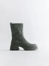 Bota corta color verde militar, con caña media, suela track y elástico lateral.