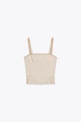 Top corto de escote recto y tirantes finos, con estampado de cuadros vichy en tonos beige y blanco. Presenta tejido elástico tipo nido de abeja en la espalda, detalle de botones forrados en el delantero y bajo con volantes. Cierre con cremallera lateral oculta en la costura.