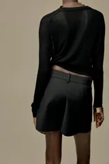 Shorts de tiro alto color negro, con trabillas en la cintura, bolsillos laterales y cierre frontal con cremallera y ganchos metálicos.