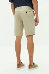 Bermuda de gabardina color verde militar, con bolsillos laterales y traseros, cierre con cremallera y botón, y trabillas para cinturón.