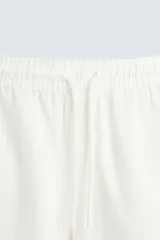 Bermuda de algodón color marrón oscuro, de corte regular fit, con cintura elástica ajustable mediante cordón. Presenta bolsillos laterales y un bolsillo trasero de vivo.