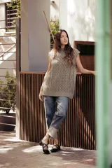 Chaleco de punto color crema con cuello alto y diseño de trenzas.