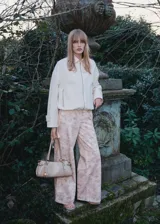 Pantalón de jean de corte wide leg con estampado floral en tonos pastel. Tiene tiro alto, cinco bolsillos, trabillas y cierre frontal con cremallera y botón.