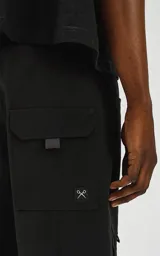 Bermuda negra de calce relax-fit, confeccionada en nylon y spandex, con tejido repelente al agua. Presenta cintura con elástico y cordón de ajuste, bolsillos delanteros con fuelle y grandes bolsillos cargo laterales con tapa. Incluye un cinturón de cinta ajustable con hebilla de plástico.