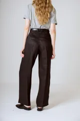 Pantalón negro de corte ancho y tiro alto, con pinzas en la cintura y bolsillos laterales.